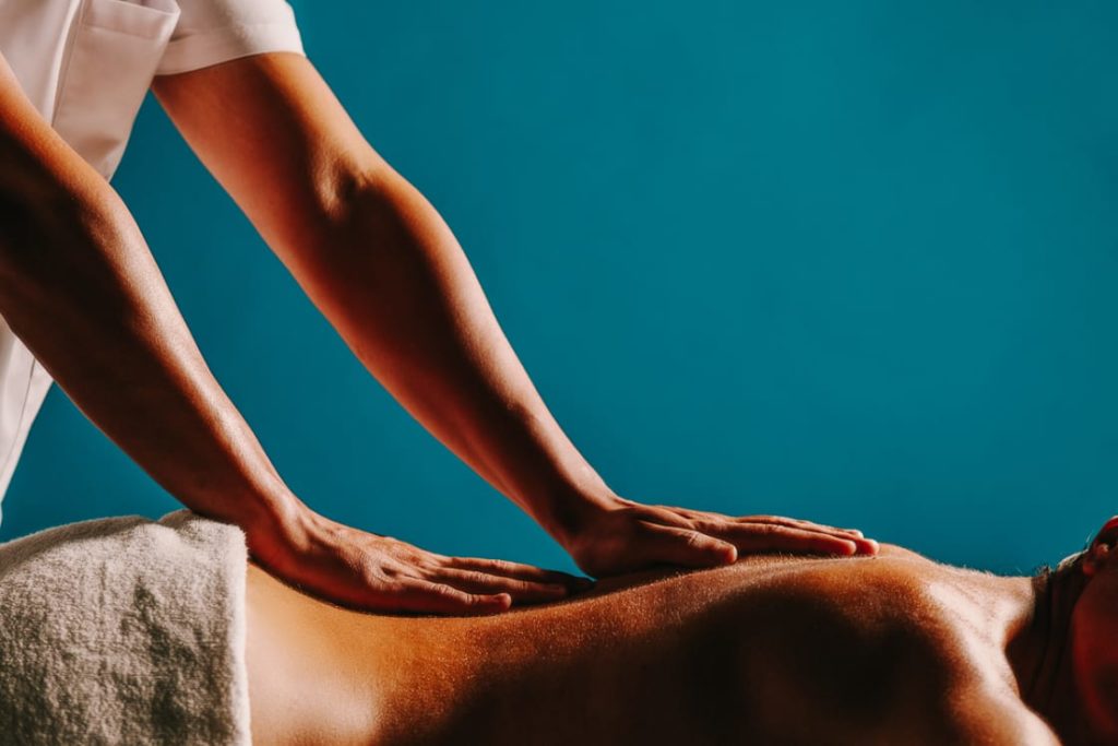 Homem fazendo massagem nas costas de uma mulher.