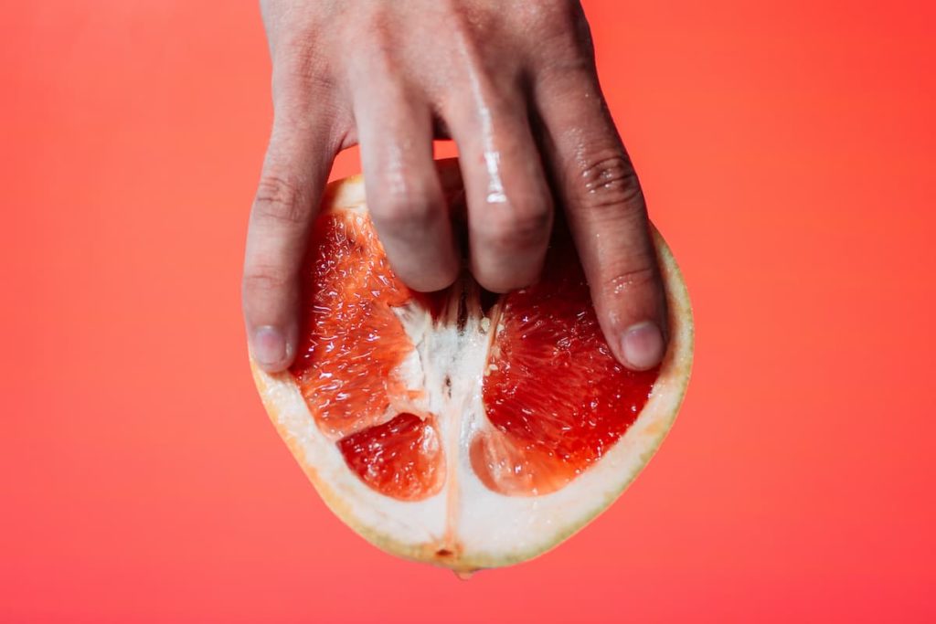Dedos masculinos acariciando uma fruta, com conotações sexuais.